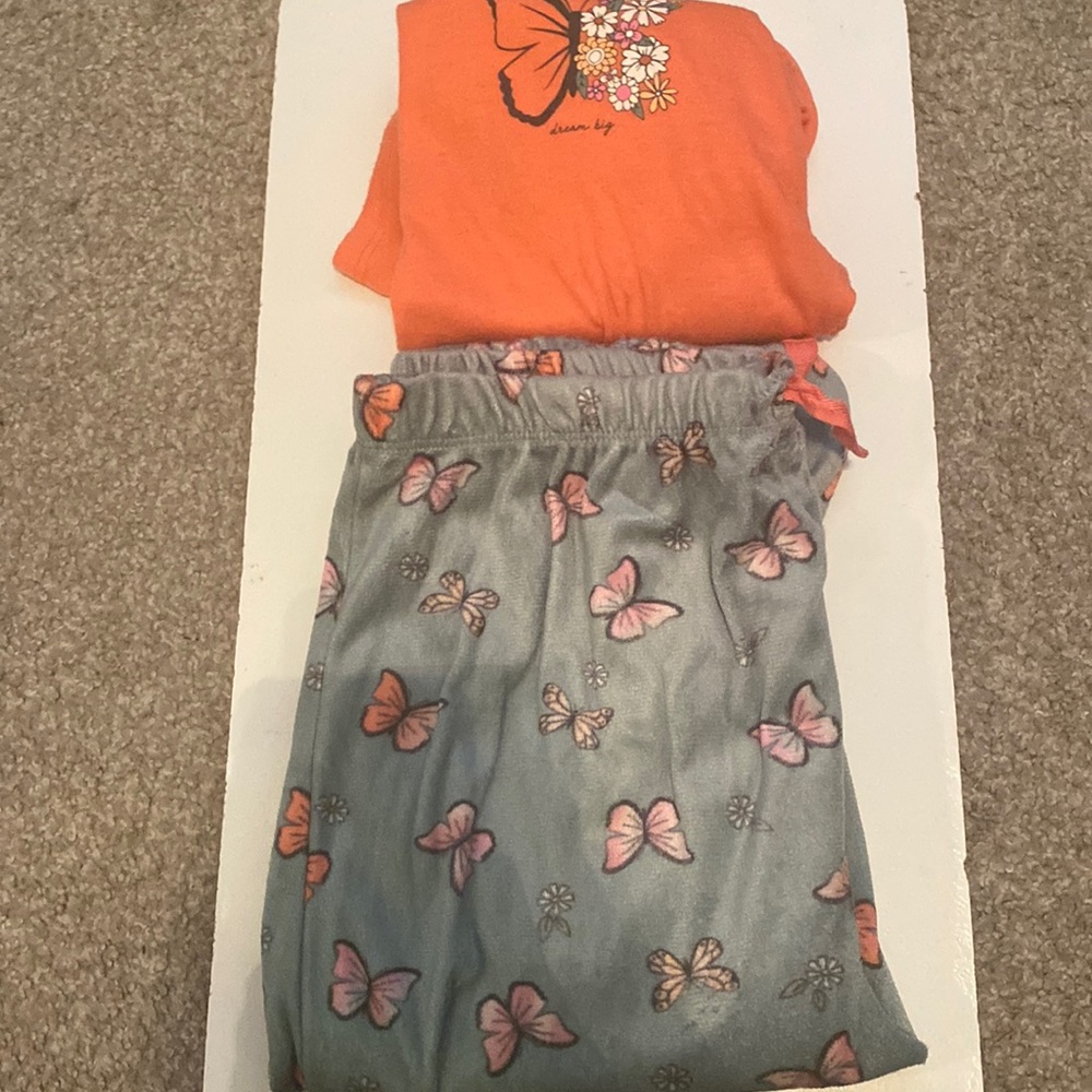 The pants it has pink and purple butterflies,on the shirt it, it says dream big.